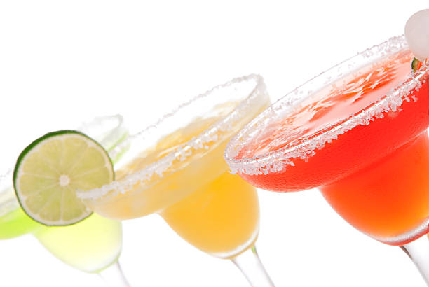 Strawberry, lime, apple Margaritas cocktails composition decorated with twisted lime, mint, cherry, cocktail umbrella in margarita glass on a white background