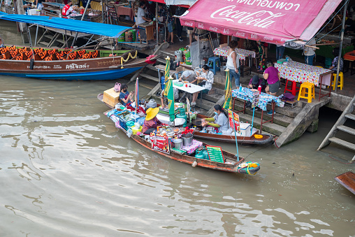 Samut Sakhon, Thailand - April, 17 2022:  Amphawa Floating Market, Thailand. Amphawa Canal is occupied by vendors who pack their boats with Food and drinks, such as fried sea mussel, noodles, coffee, O-liang (iced black coffee), sweets, etc