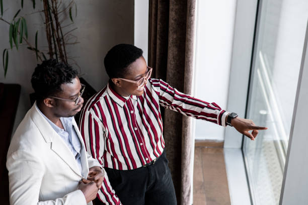 istock Two young black businesspeople looking through a window 1394750198