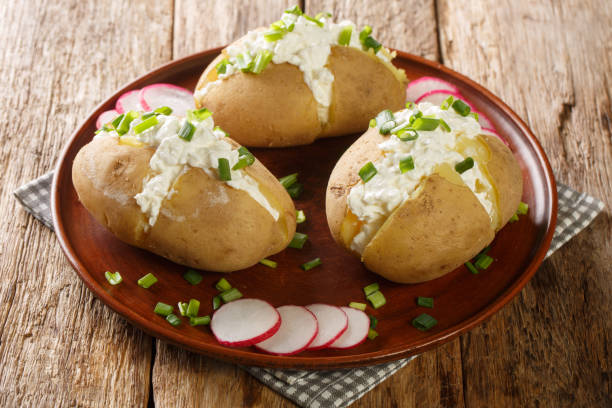 Classic Poznan specialty pyry z gzikiem is a simple potato and cheese dish close-up in a plate. Horizontal Classic Poznan specialty pyry z gzikiem is a simple potato and cheese dish close-up in a plate on a wooden table. Horizontal baked potato sour cream stock pictures, royalty-free photos & images