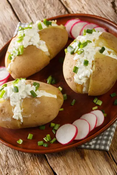 Photo of Pyry z gzikiem is a dish of Poland cuisine which consists of potatoes in jacket, salty curd cheese and green onion closeup on the plate. Vertical