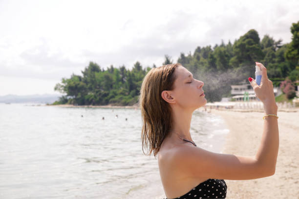 Woman spraying facial mist on her face, summertime skincare concept Woman spraying facial mist on her face, summertime skincare concept vacation rental mask stock pictures, royalty-free photos & images