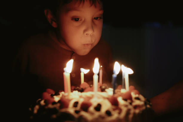 istock Cute caucasian boy blowing up candles pn birthday cake. Image with selective focus 1394752364