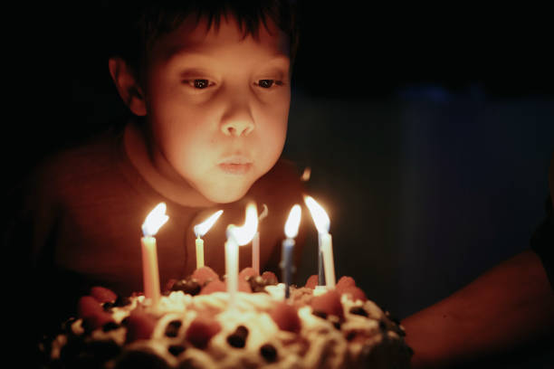 istock Cute caucasian boy blowing up candles pn birthday cake. Image with selective focus 1394752368