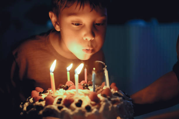 Cute caucasian boy blowing up candles pn birthday cake. Image with selective focus
