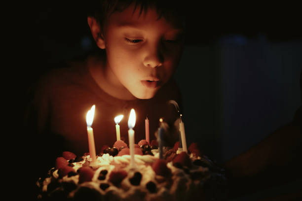 istock Cute caucasian boy blowing up candles pn birthday cake. Image with selective focus 1394752375