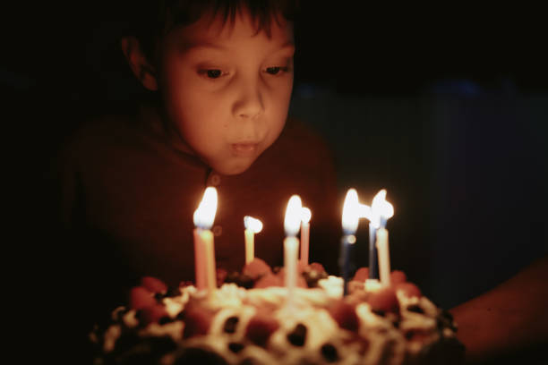 istock Cute caucasian boy blowing up candles pn birthday cake. Image with selective focus 1394752416