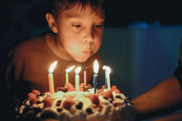 istock Cute caucasian boy blowing up candles pn birthday cake. Image with selective focus 1394752428