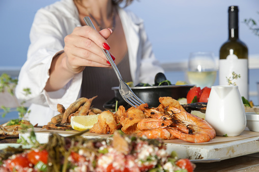 Mujer joven disfrutando de platos de mariscos durante la puesta de sol en el restaurante de la playa photo