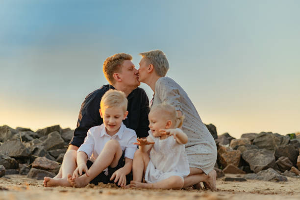 아기를 기대하는 행복한 백인 가족. 엄마의 배를 만지는 소녀. 사랑하는 아들과 남편이 부드러워 보입니다. 해변에서 일몰을 즐기십시오. 고품질 사진 - human pregnancy baby shower image color image 뉴스 사진 이미지
