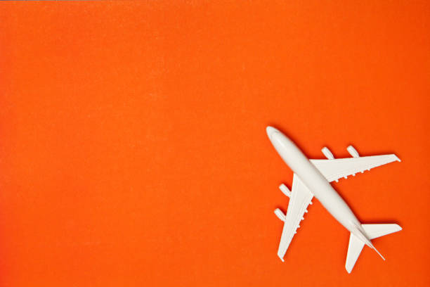 istock Airplane model. White plane on orange background. Travel vacation concept. Summer background. Flat lay. 1394757790