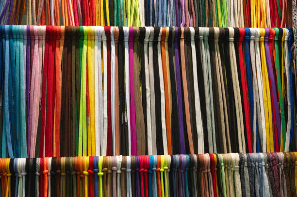 Large collection of different colorful lace samples hangs tied on rack bars in hallway at industrial exhibition close view