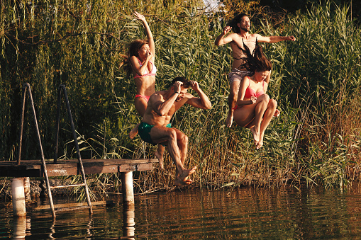 Group of young people enjoy a summer day and jump into the river