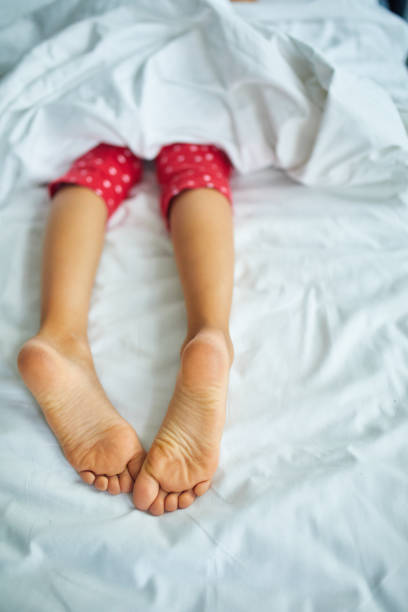 istock Girl's feet covered with white bed sheet, sleeping in a comfortable bed 1394759235