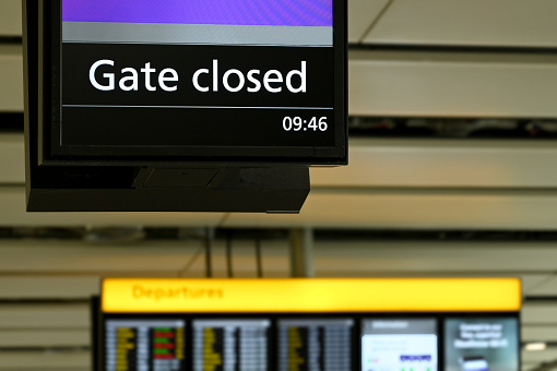Electronic display in an airport terminal showing passengers the gate for borading the plane has closed. No people.