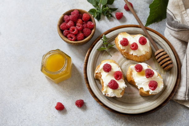 Healthy summer breakfast with sweet sandwiches with ricotta, raspberries and honey on a stone table. Copy space. Healthy summer breakfast with sweet sandwiches with ricotta, raspberries and honey on a stone table. Copy space. crostini photos stock pictures, royalty-free photos & images