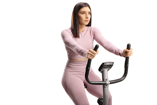 Young fit woman in sportswear on a stationary bike isolated on white background