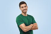 istock Attractive joyful handsome sporty man in green t-shirt standing with crossed arms 1394760858