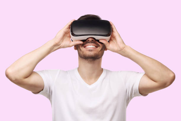 istock Young smiling man wearing virtual reality headset or VR glasses, playing video game 1394761477