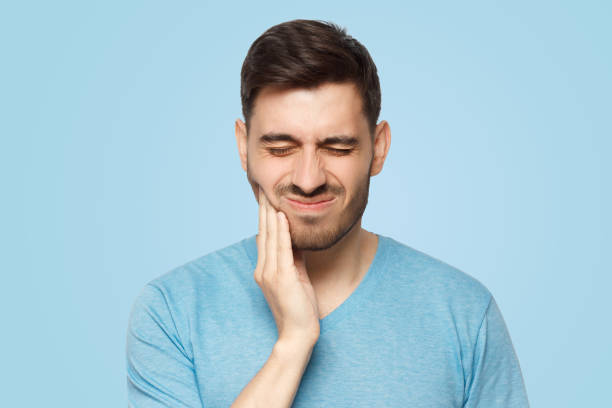istock Young man with closed eyes suffering from severe toothache, touching jaw with fingers 1394761504