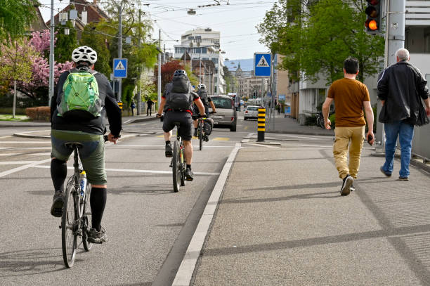 les gens rentrent du travail à vélo et à pied à bâle - protective suit photos photos et images de collection