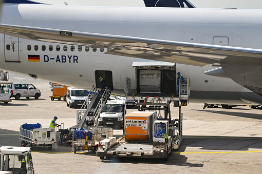 Frankfurt, Germany - April 2022: Air freight cargo and luggage being unloaded into the hold of a Lufthansa Boeing 747 jet.