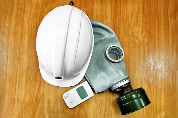 The white helmet, gas mask and dosimeter The white helmet, gas mask and a dosimeter on the background of a wooden tabletop radiation dosimeter stock pictures, royalty-free photos & images