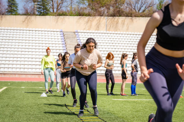 Athletes running ladder drills on a green turf field