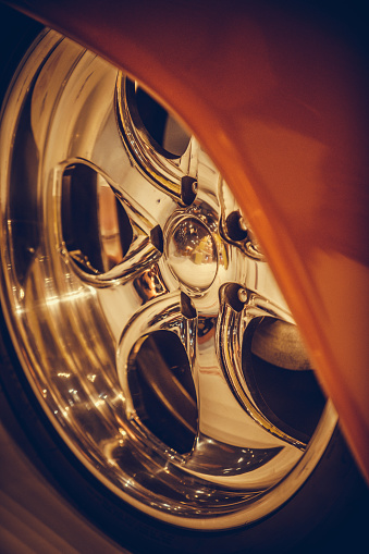 Close up shot of a chrome classic wheel rim on a vintage car.