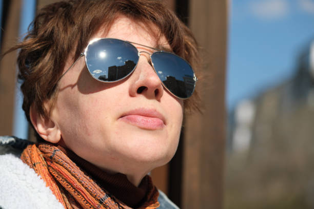 Woman wearing reflecting sunglasses is looking at the sky