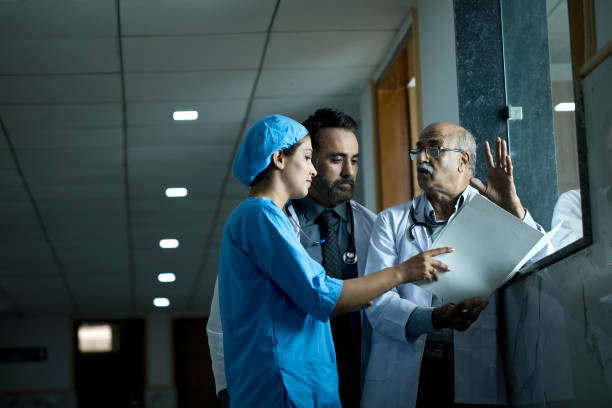 Medical practitioners having a discussion in a hospital Doctors and nurse discussing over a medical report at hospital corridor india hospital stock pictures, royalty-free photos & images