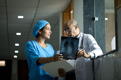Old doctor and nurse examining medical x-ray at hospital corridor