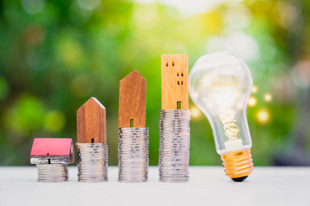 Wood house model and row of coin money with a light bulb . Money management, financial plan, business idea and Creative ideas for saving money concept. stock photo