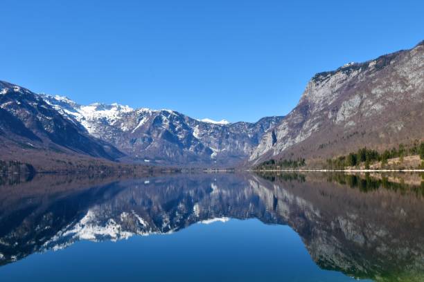 schneebedeckte berggipfel in den julischen alpen und im bohinjer see mit der spiegelung der berge im see in gorenjska, slowenien - julian alps mountain lake reflection stock-fotos und bilder