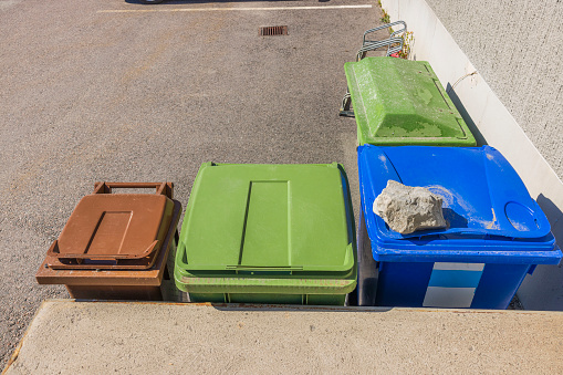 Close-up top view of three garbage sorting bins and sand container. Sweden.