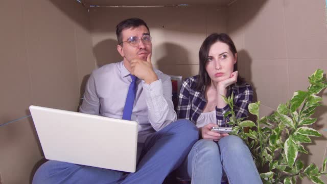 Concept idea of a little room,frustrated young married couple huddled in a tight box