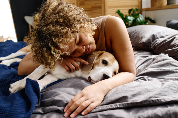 istock Woman cuddling with dogs on bed 1394774841