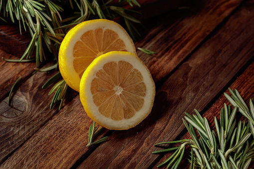Rosemary and lemon slices on an old wooden table. Copy space.