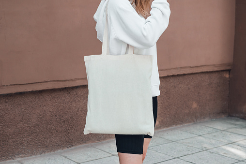 Young woman with white cotton bag on her shoulder. Mock up.