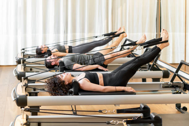 Class of diverse people doing the hundred pilates exercise stock photo