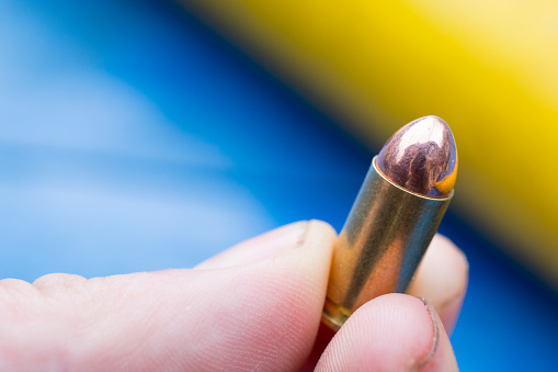 Close-up of man holding a 9 mm bullet.