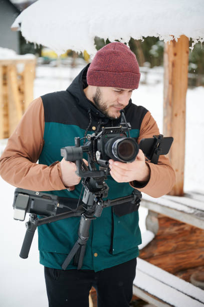istock videographer man with camera mounted on gimbal stabilizer equipment in winter. 1394786906