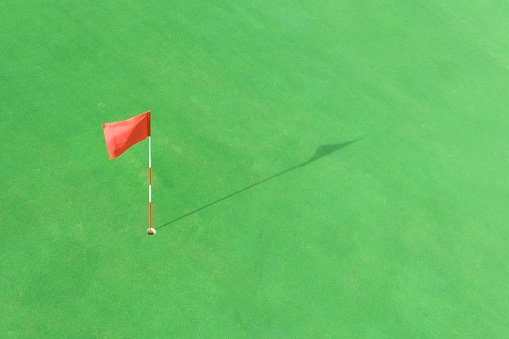 This is a stock photo of a female driver at the top of a hill getting ready to tee off with a driver. The background is a blue sky allowing for lots of copy above her. This is a real clean colorful graphic image.