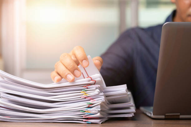 istock Businessman hand pick up Stack overload documents report paper with colorful paperclip with fair light to analyze data 1394788025