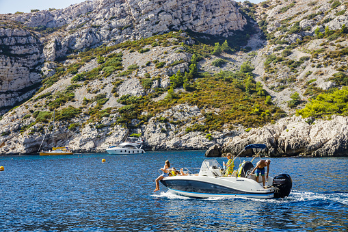 Tourists onboard of a motor boat sailing in the Calanque of Sugiton in Marseille, France