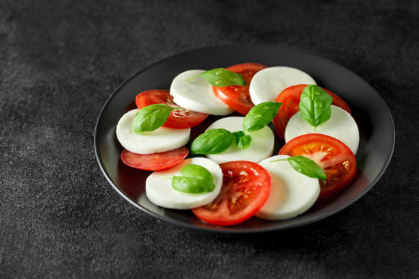 istock Caprese - salad tomatoes, mozzarella and basil, Italian appetizer, on dark background, selective focus. 1394790786