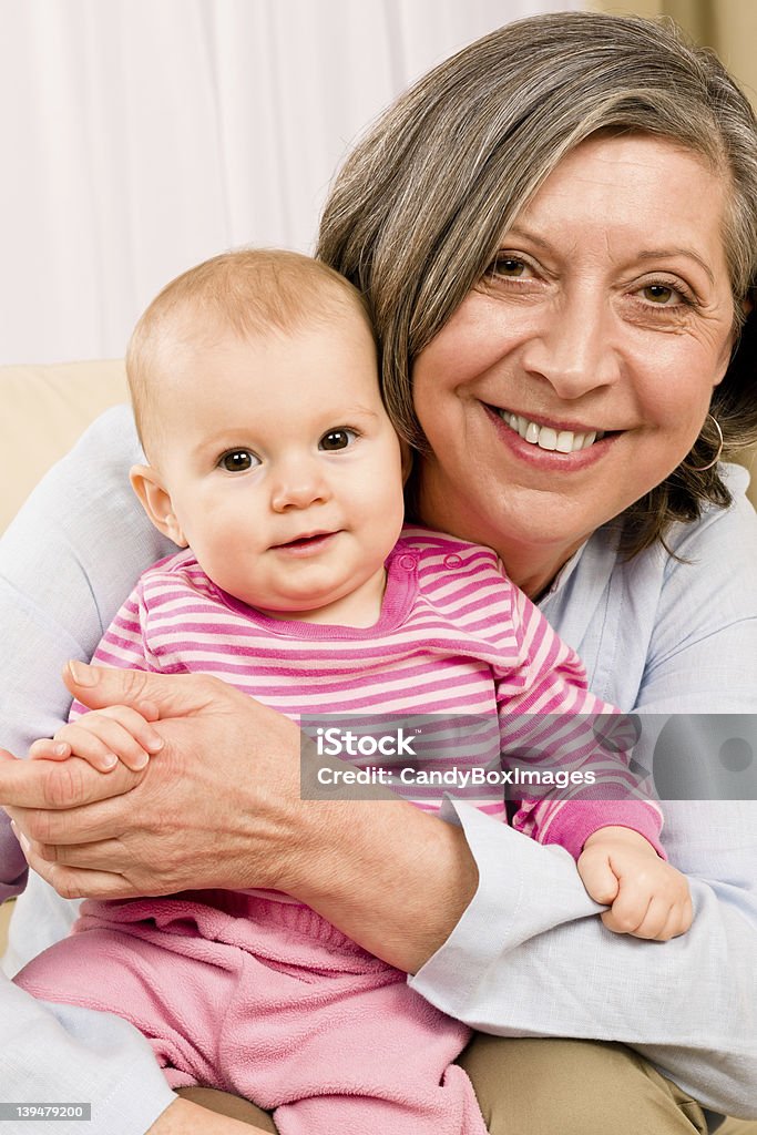 Grandmother hold little baby girl smiling Senior woman hold little baby girl cute smiling close-up 60-69 Years Stock Photo