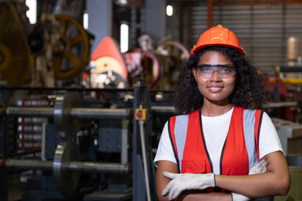 istock African women mechanical engineer, wearing safety equipment.  While do safety control while work inside of factory area. with heavy production machine inside factory at the background. 1394795569