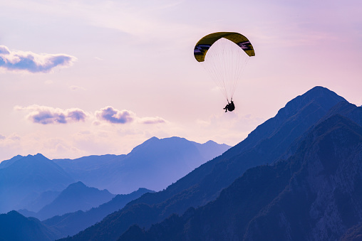 Dream flight in the mountains. Paraglider in the sunset sky of Bordano, Italy