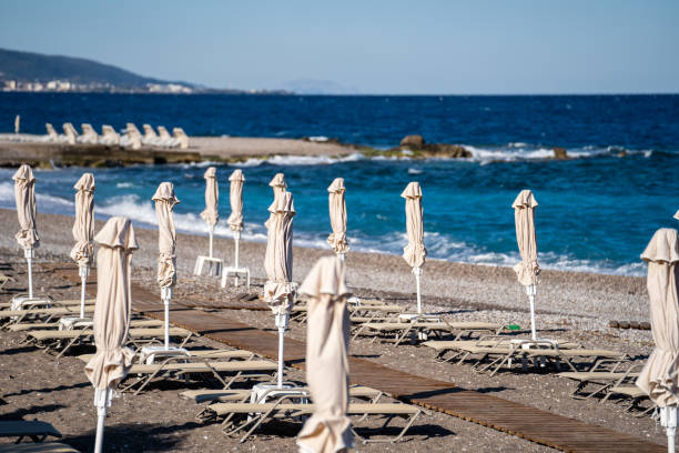 istock Empty beach chairs and closed  sun umbrellas on the beach in Greece. 1394798774